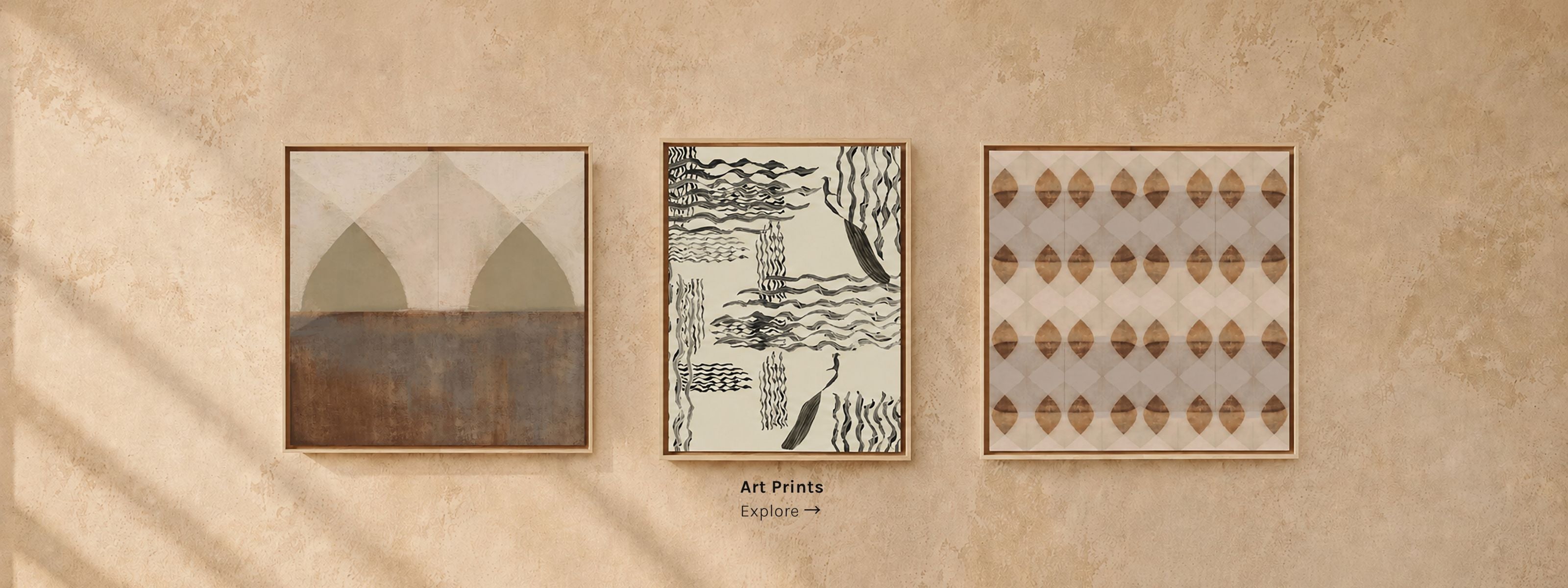 Three framed abstract art prints in earthy tones, displayed on a weathered plaster wall