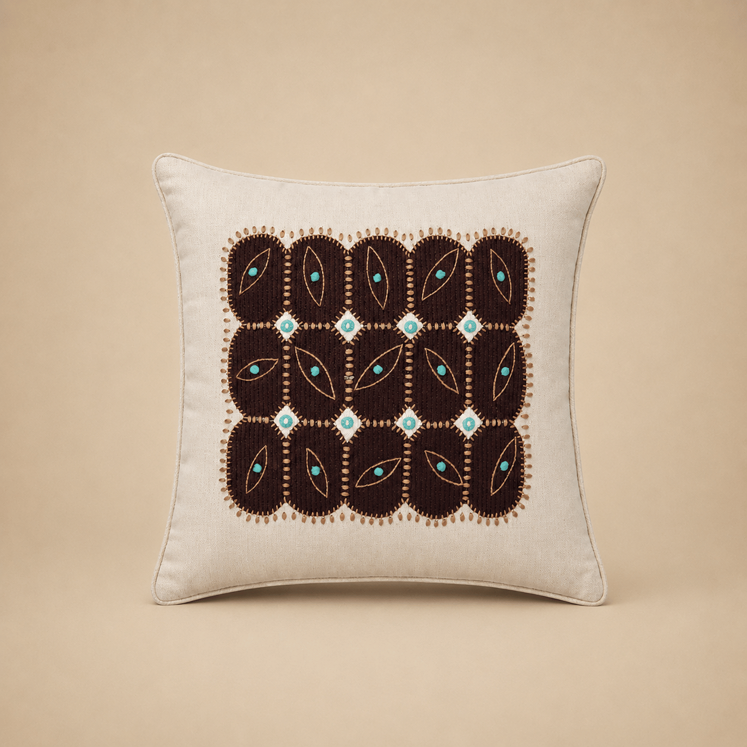 Anokha cushion cover with a grid of embroidered leaf motifs in turquoise and deep brown on cream cotton
