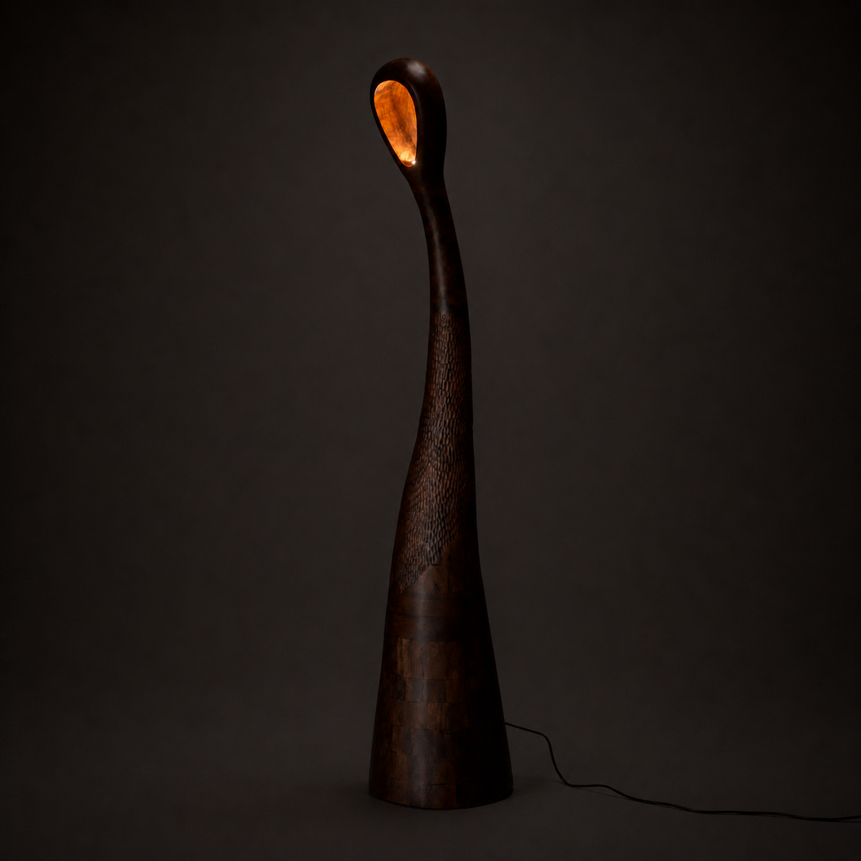 Chhaav floor lamp lit from within, its tall hand-carved wood form glowing against a dark backdrop