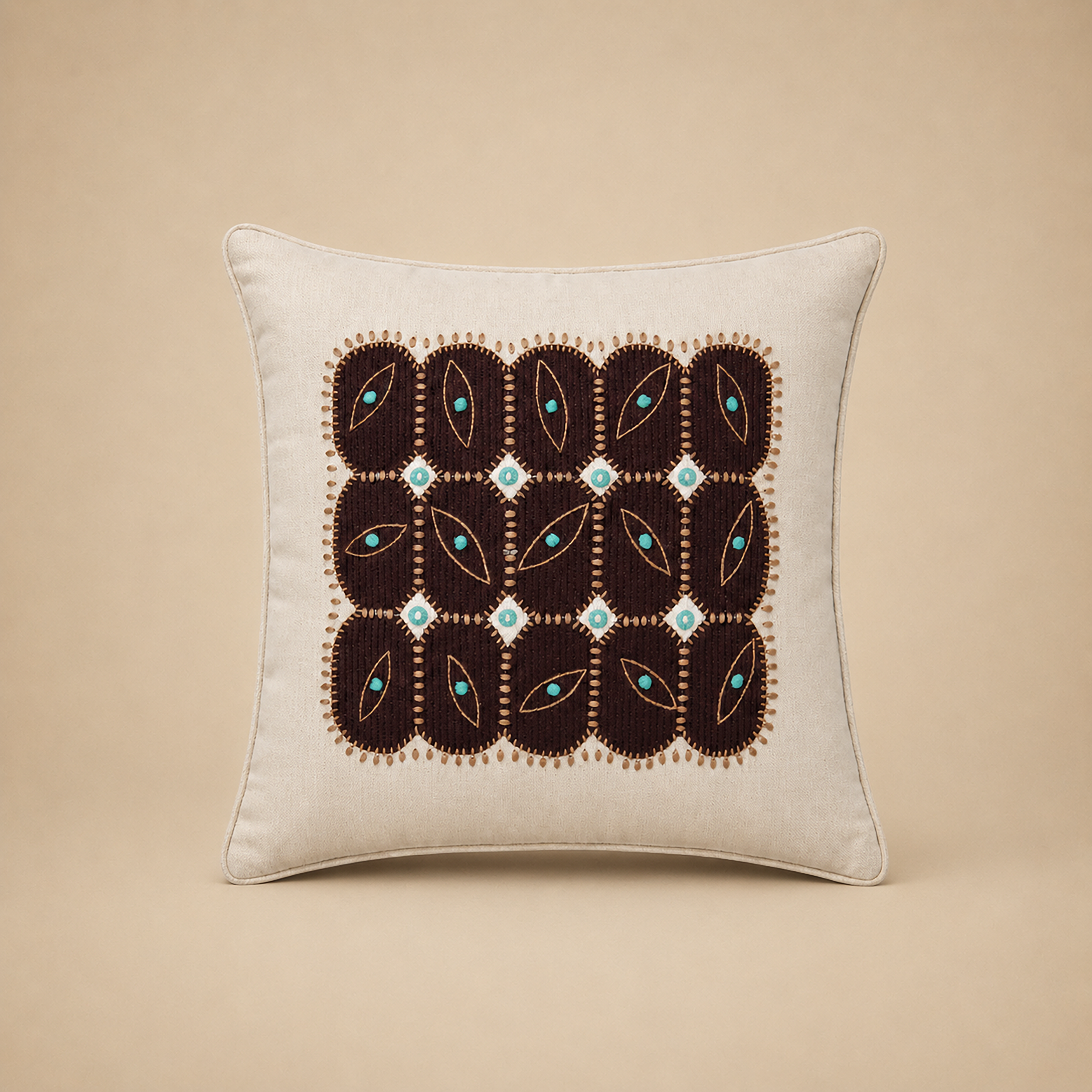 Anokha cushion cover with a grid of embroidered leaf motifs in turquoise and deep brown on cream cotton